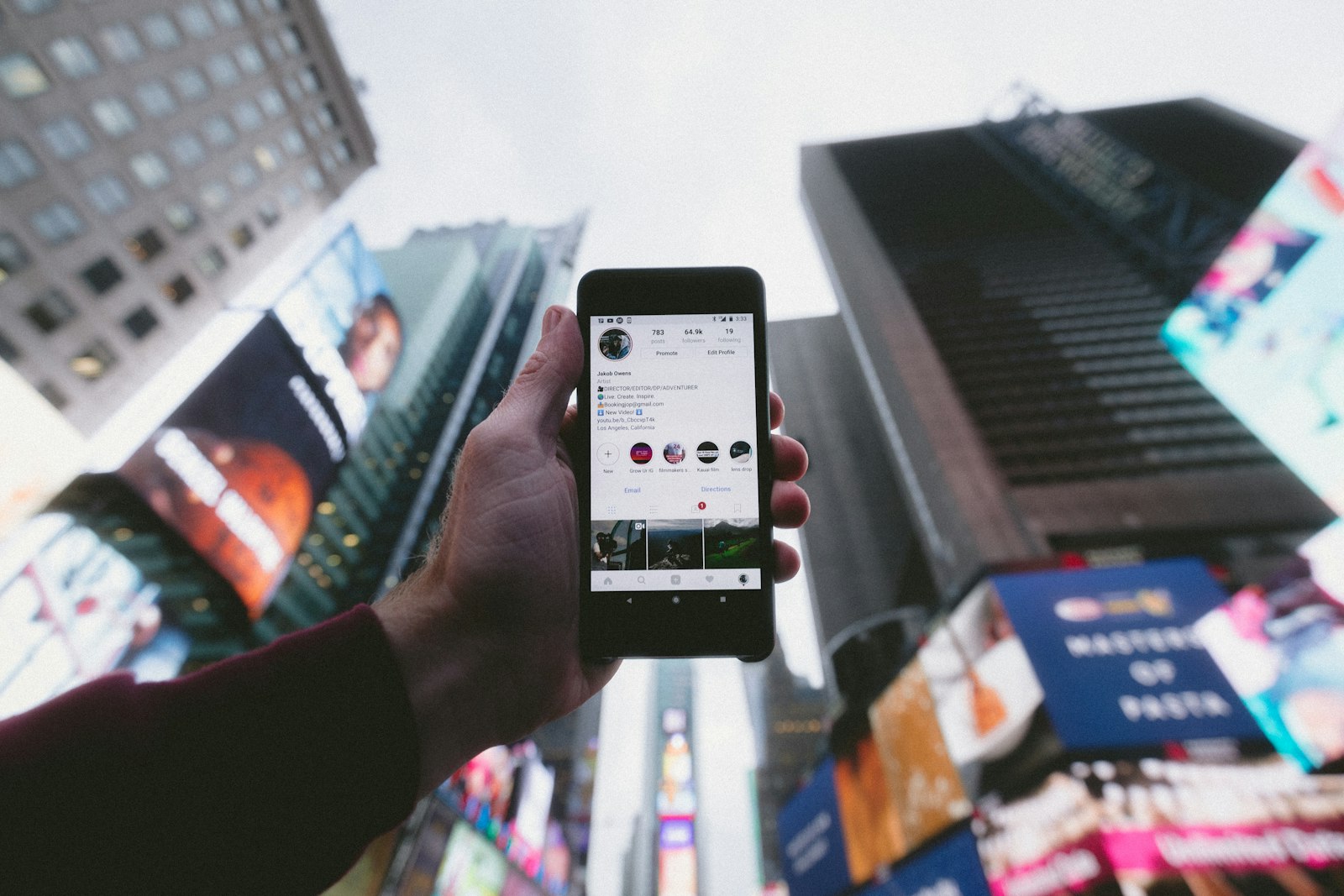 Persona sosteniendo un teléfono inteligente frente a un entorno urbano